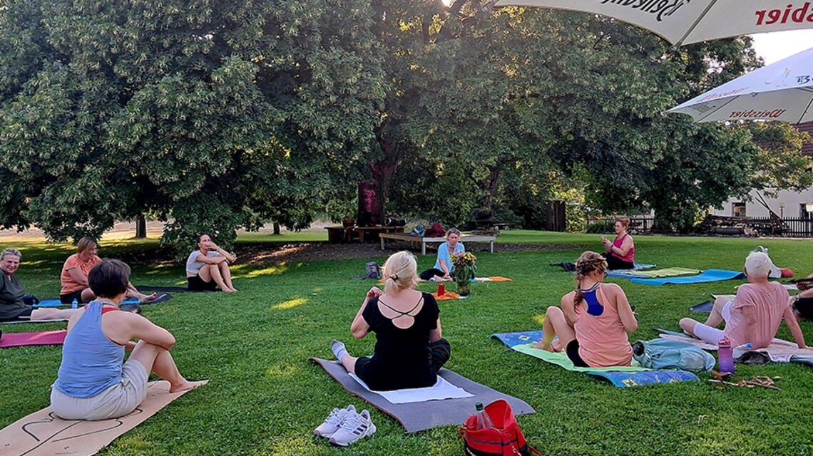 Bild zeigt die Teilnehmerinnen der Yogastunde jeweils mit Anna Borsch und Katharina David auf der Mühleninsel der Bettinger Mühle.
