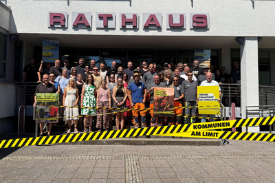 Bild zeigt Mitarbeiter/-innen mit Bürgermeister Wolfram Lang vor dem Rathaus der Gemeinde Schmelz anlässlich der "Kommunen am Limit" Aktion am 22.06.2026